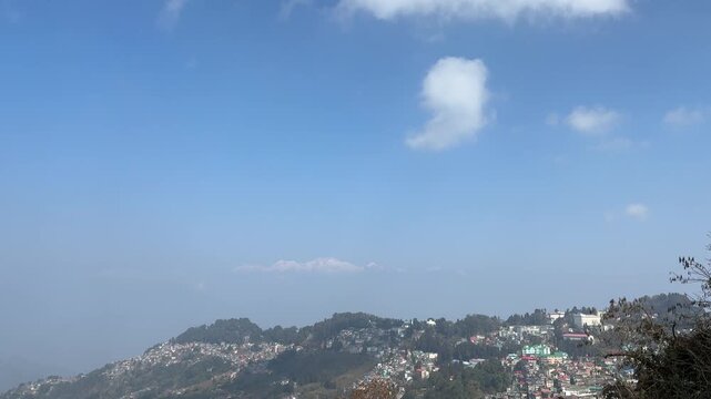 View of houses perched on the steep green hills with Kanchenjunga mountain on the way to Darjeeling
