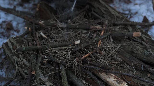 Starting a fire with a flint in winter: a close-up of hands using a flint to light dry twigs in a snow-covered open landscape. This scene illustrates survival skills and mastery of the wilderness.