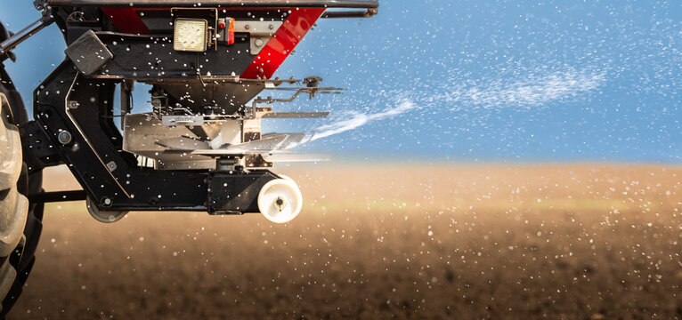 Tractor spreading artificial fertilizers in field
