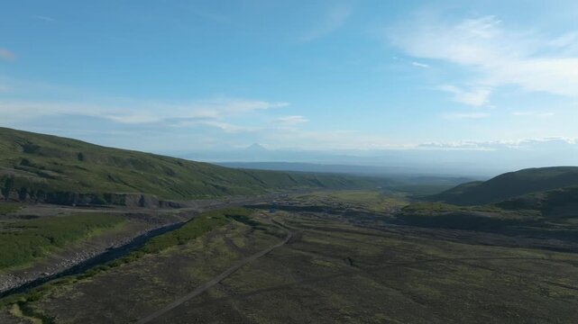 Wide aerial landscape of the Sukhaya River dry channel and gravel road on the route to Avachinsky Volcano, Kamchatka Krai, Russia, under clear blue sky