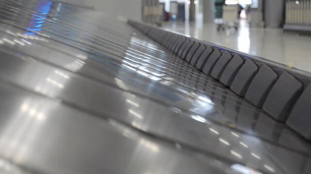 Baggage claim conveyor belt in an airport terminal with metallic surface reflecting belt plate emputy of any luggage bag, showcasing the continuous flow of luggage belt at airport without any luggage