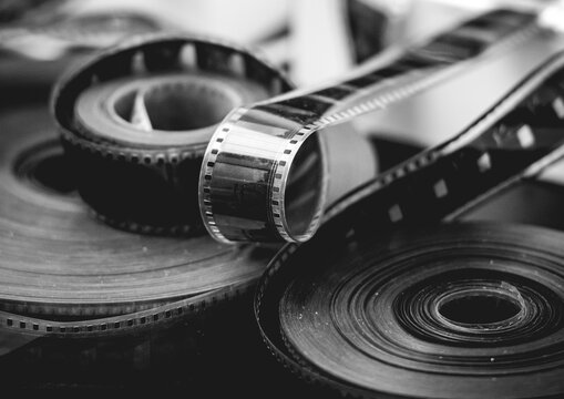 Black and white close-up of vintage photographic film rolls and negatives, symbolizing analog photography and classic film production