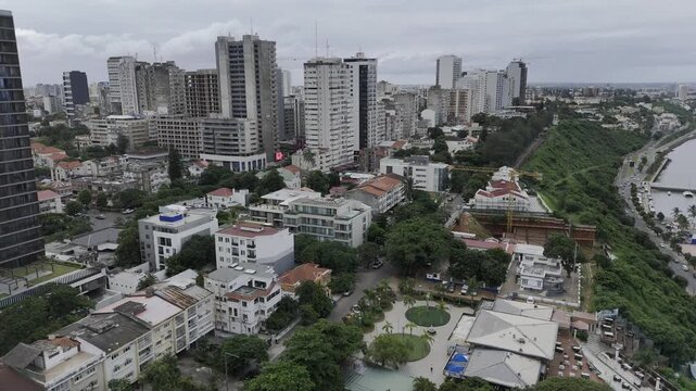Drone lowers with view of high rise buildings lining coastal highway next to Parque dos Namorados on an overcast day in Maputo, Mozambique