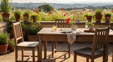 Obraz premium Sunny outdoor patio with wooden dining set, potted plants, and scenic countryside view.