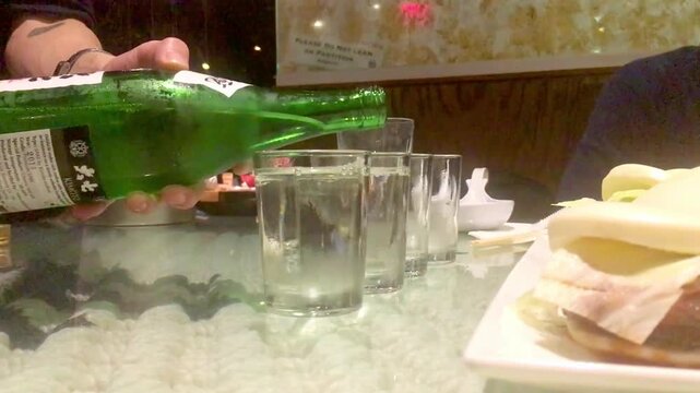 Slow Motion Pouring of Japanese Sake into Glass Cups at Restaurant in 4K
