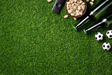 Naklejka premium A mini soccer balls, green beer bottles, pistachios and TV remote create a perfect match day atmosphere. Top view.