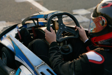 Naklejka premium A focused racer grips the steering wheel of a go-kart, ready to hit the track