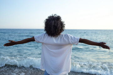 Woman with arms outstretched embracing the ocean breeze on a sunny day © SISMIZ