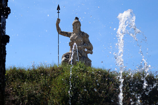 Statua monumentale della dea Minerva o Roma con lancia svettante sopra una siepe nei giardini di Villa d'Este a Tivoli con giochi e spruzzi d'acqua in primo piano