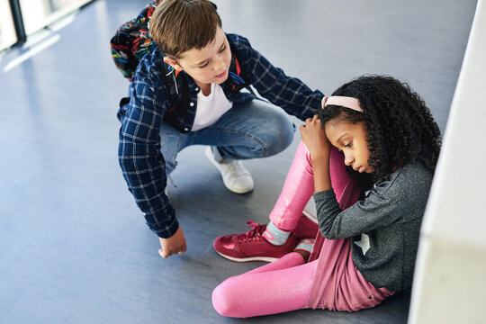 Education, children and sad with comfort in hallway for bullying, emotional support and inclusion. Kid students, unhappy girl and friend with empathy in school for isolation, anxiety and intervention