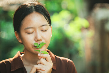 Fototapeta premium A woman is deeply inhaling the fragrant scent of fresh green herbs, which creates a sense of peace.