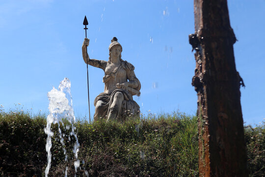 Statua monumentale della dea Minerva o Roma con lancia svettante sopra una siepe nei giardini di Villa d'Este a Tivoli con giochi e spruzzi d'acqua in primo piano