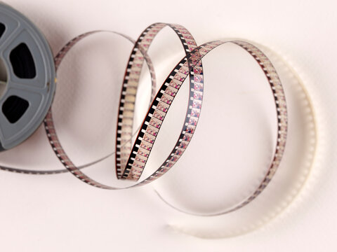 Anciennes bobines de 8 mm et Super 8. Une bobine de film vintage qui se d&eacute;roule, mettant en valeur la beaut&eacute; du cin&eacute;ma analogique. Fond uni et simple.