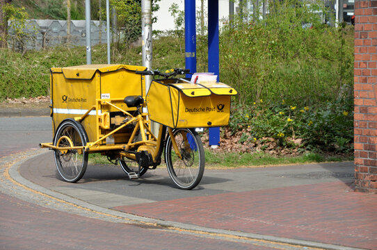 Deutsche Post, Kurierfahrer liefert Post mit dem Fahrrad in der Stadt aus