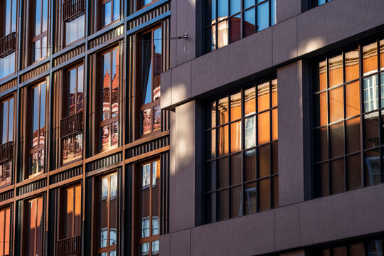 Stockholm architecture detail of a modern building facade with glass windows and reflection in warm light forming a clean pattern and rhythm