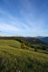Obraz premium Alpine landscape in Italy with green hills, cable car and Alps mountains