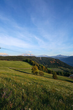 Alpine landscape in Italy with green hills, cable car and Alps mountains