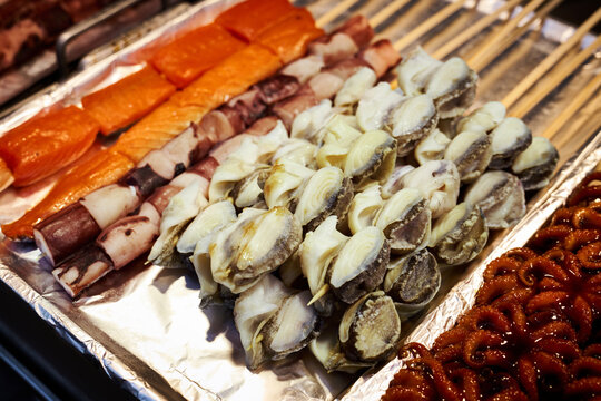 Traditional Korean street food featuring grilled abalone, octopus, and seafood skewers on a market stall