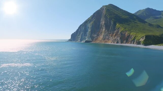 Drone footage of calm blue sea and rugged coastal mountains with steep green cliffs along Avacha Bay, near Petropavlovsk-Kamchatsky, Kamchatka Krai, Russia