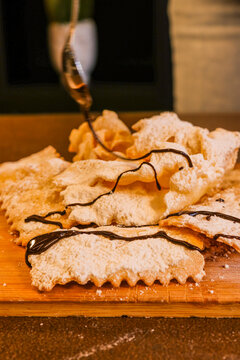 Chiacchiere fritte, dolce tradizionale napoletano, guarnite con zucchero a velo e sanguinaccio appena sfornate da una pasticceria 