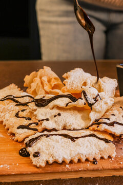 Chiacchiere fritte, dolce tradizionale napoletano, guarnite con zucchero a velo e sanguinaccio appena sfornate da una pasticceria 