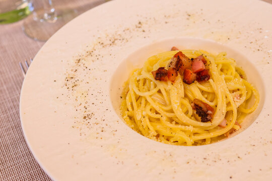 Piatto di spaghetti alla carbonara con crema di uova, guanciale croccante e pecorino romano servito in un ristorante come primo piatto