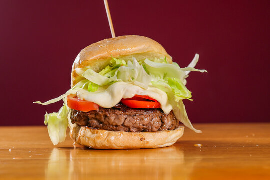 Panino pub ripieno di hamburger di carne, pomodori freschi, insalata e provola filante appena servito in una hamburgeria