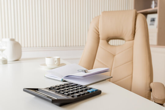 Beige leather chair, laptop and desk in office.Modern workplace.Stylish workplace with laptop, cup of coffee. elegant personal accessories in home decor.