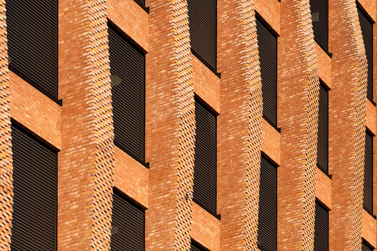 Modern brick facade with windows and pattern repetition delivers tactile texture as building architecture reads abstract for corporate backdrops