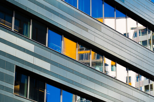 Windows and lines set a modern facade rhythm as color accents push corporate building architecture toward an abstract pattern background