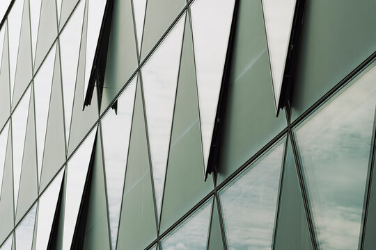 Abstract corporate story in reflections on a modern glass facade where triangles pattern shapes the building architecture into crisp geometry