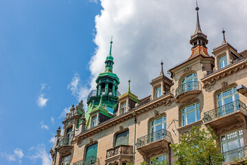 This historic building in central Zurich showcases neo-Baroque architecture with green copper roofs, decorative balconies, and elegant turrets under a clear blue sky. © Sergey