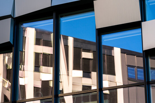 Modern glass facade turns windows into a mirror where reflection builds abstract pattern with distortion held in symmetry of architecture
