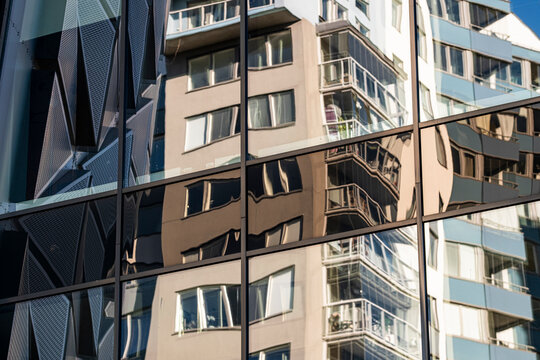 Reflection on glass windows turns a modern facade into abstract urban architecture pattern with subtle distortion and layered geometry