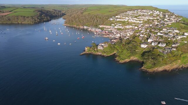 Aerial view of Fowey Harbour and Polruan with numerous boats moored in the estuary surrounded by lush green hills and coastal houses in Fowey, England, United Kingdom.