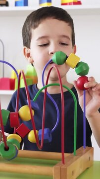 Adorable little boy playing with roller coaster maze toy skill at home