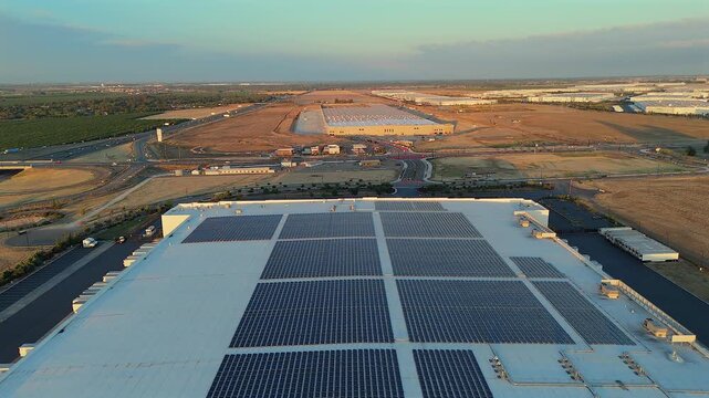 Aerial view of warehouse roof with solar panels at sunset