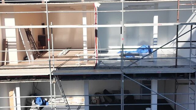Building renovation in progress with scaffolding and exposed interior spaces. Exterior view of a building undergoing extensive renovation, showcasing scaffolding and unfinished interior rooms with