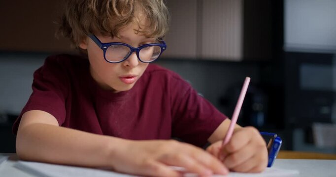 Focused Youth Practicing Penmanship Quietly. Young Male Diligently Practicing Handwriting At Desk