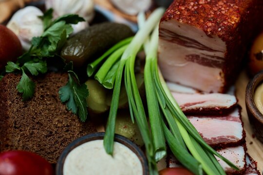 Traditional Ukrainian lard with spices, rye bread, pickles and green onions, rustic appetizer close-up