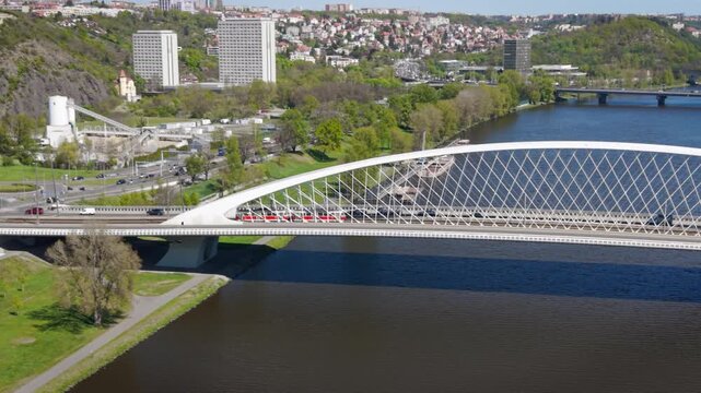 Aerial view of modern Troja Bridge with public transport tram and bus crossing Vltava river toward Hole&scaron;ovice district in Prague on a sunny day