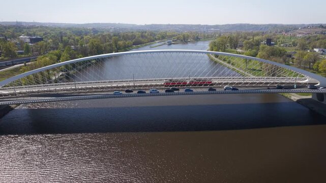 Aerial view of modern Troja Bridge with public transport tram and bus crossing Vltava river toward Hole&scaron;ovice district in Prague on a sunny day