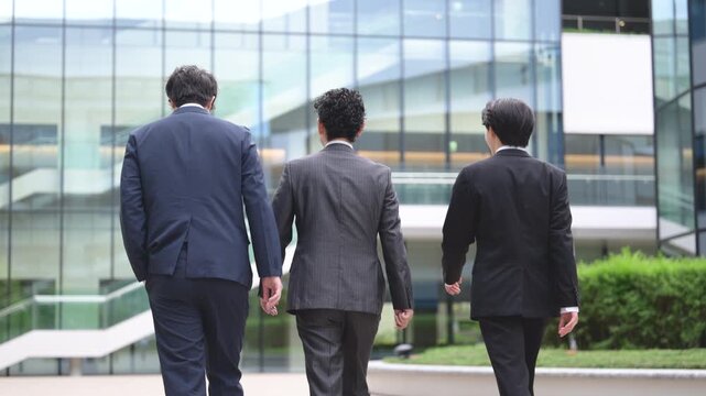 A handsome sales team of three walking side by side against a backdrop of city skyscrapers; a faceless video conveying a positive image of corporate sales and business growth, featuring individuals ra