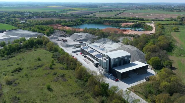 Aerial view of Foamed Glass UK Industrial Factory with piles of aggregate and a nearby lake in Great Heck, England, United Kingdom.