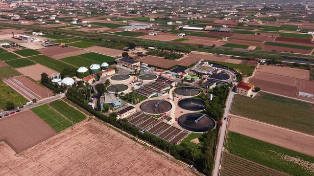 Modern wastewater treatment plant in Spain surrounded by farmland, featuring circular clarifiers, activated sludge tanks, biogas digesters and biological nutrient removal facilities