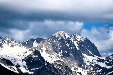 Obraz premium High mountain peak covered with snow under a dramatic cloudy sky in winter season.