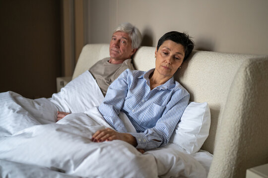 Loneliness and intimacy problems at older age in marriage, silent senior woman avoiding contact with partner, elder husband and wife in bed experiencing relationships problems and difficulties.