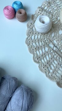 A woman's hand gently picks up a ball of thread. Hobby, crochet. Tangles, crochet hooks, a white table. Peace from the simplest things