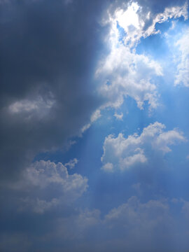 Dramatic Vertical View of Sun Hiding Behind Clouds with Silver Lining Effect