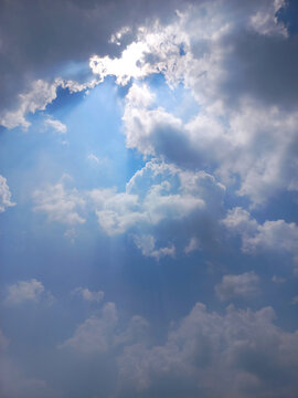 Dramatic Vertical View of Sun Hiding Behind Clouds with Silver Lining Effect